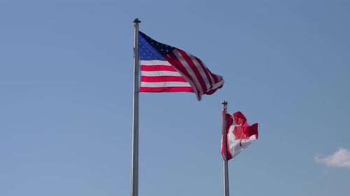 Flags of USA and Canada Waving on a Sunny Day