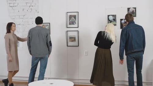 Men and Women in an Art Gallery Inspect the Abstract Works of Contemporary Artists