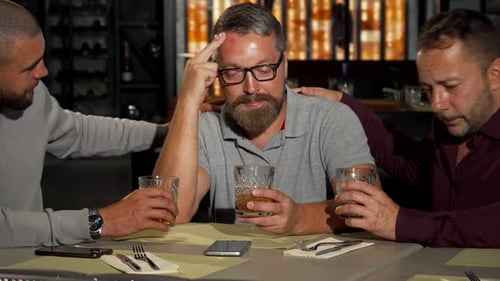 Two Mature Men Supporting Their Upset Friend While Drinking at the Bar