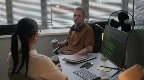 Junger männlicher Programmierer chattet mit seiner jungen Kollegin im IT-Büro