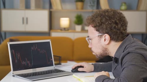 Man Analyzing Financial Data on Laptop at Desk