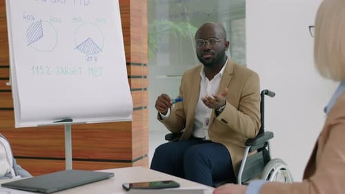 Black Businessman in Wheelchair Giving Presentation on Office Meeting