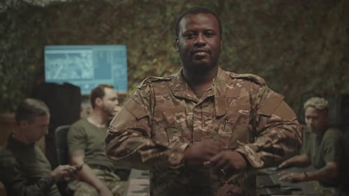 Man in Camouflage Uniform Arms Crossed in Command Center