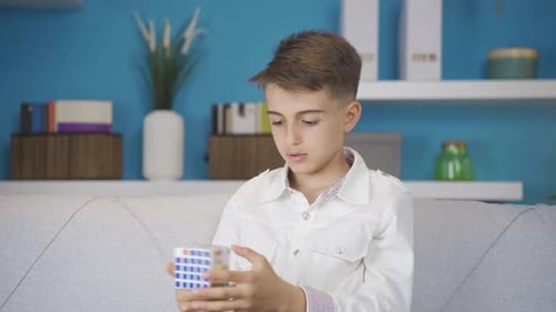 Child plays with colorful Rubix cube on a couch