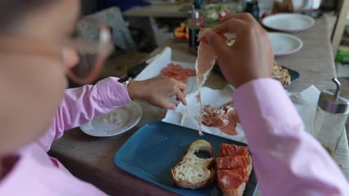 Person Preparing Bread Appetizers With Thin Sliced Meat