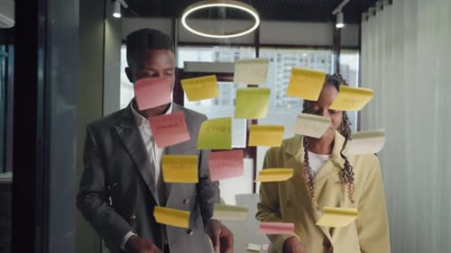 Office Workers Sticking Notes on Glass in Office Brainstorming and Generating Idea for Business