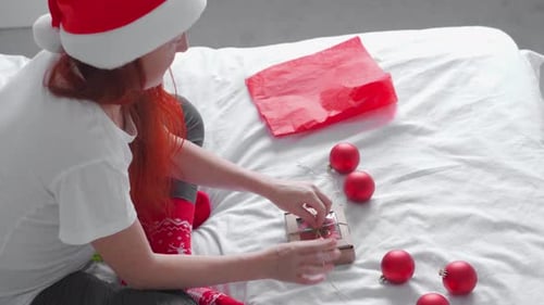 Woman Wrapping Christmas Gift on Bed