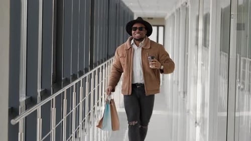 black stylish young man walking down the mall after shopping
