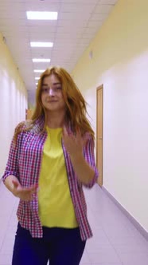 Femme aux cheveux longs marchant dans un couloir bien éclairé avec des portes de chaque côté