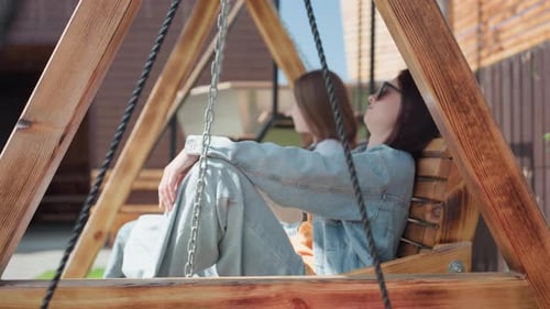 Women Relaxing Together on a Wooden Porch Swing