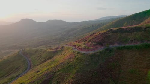 Epic Aerial of Winding Hillside Road at Hazy Sunrise