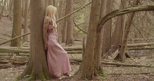 Black Girl With Long Blonde Hair, Wearing A Pink Gown, Leans Against A Tree In The Forest. Wide Shot
