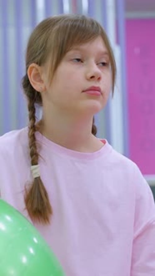 Young Girl in Pink Sitting Near Green Stability Ball in Gym