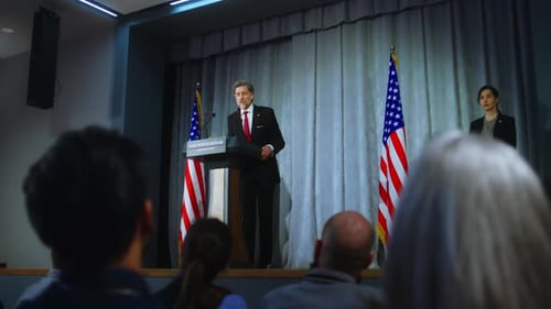 Man in Suit Giving Speech at Podium