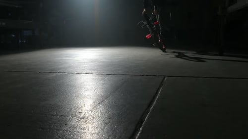 Young bmx rider performs dangerous tricks in dark urban warehouse