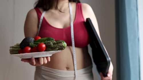 Woman Holding Vegetables and Scale for Weight Loss