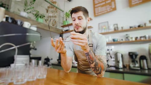 In a Cozy and Friendly Cafe a Tired Barista is Leaning Against the Counter Taking a Brief Moment to
