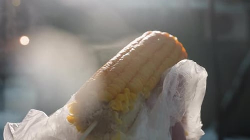 Close Up of Rotating Eaten Corn with Steam Rising and Bokeh Lights in Background
