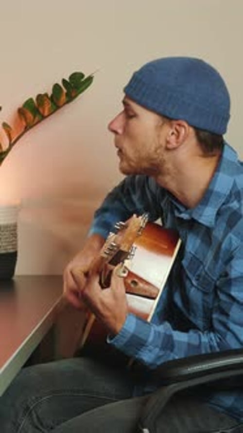 Young Adult Playing Acoustic Guitar at Desk