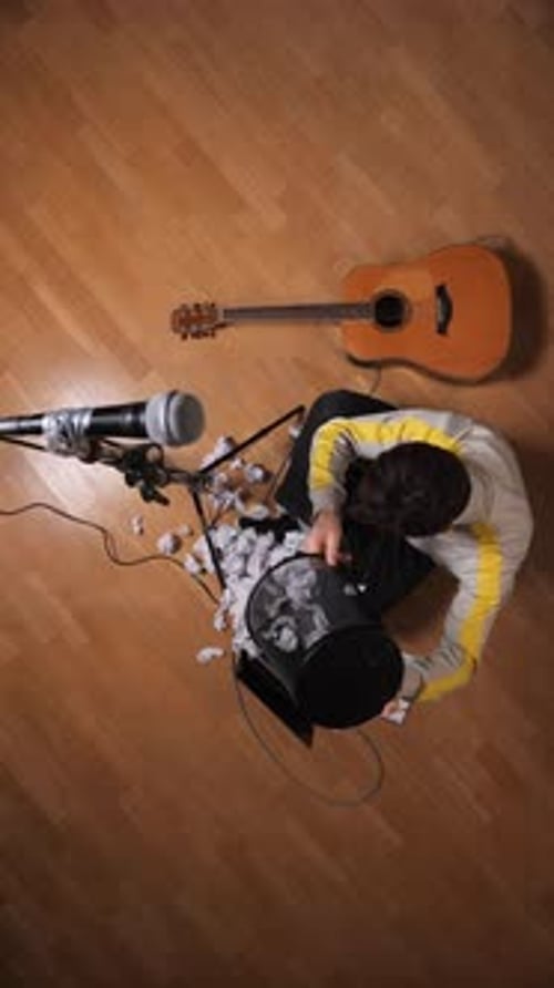 Struggling Songwriter Writting With Crumpled Papers From Above