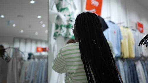 Cheerful Woman Takes Dress From Rack in Clothing Store