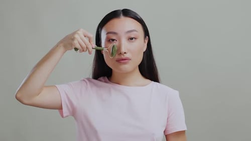 Woman using jade face roller for skincare routine