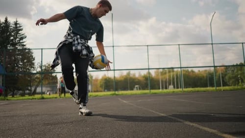 Athlete Traps Volleyball and Poses Smiling in Outdoor Court with People Walking