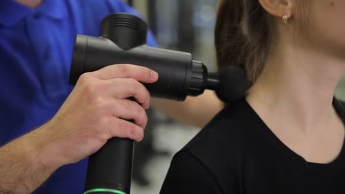 The Doctor Massages the Patient's Neck Using an Electronic Massager