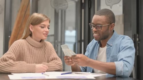 Man handing cash to woman at office desk