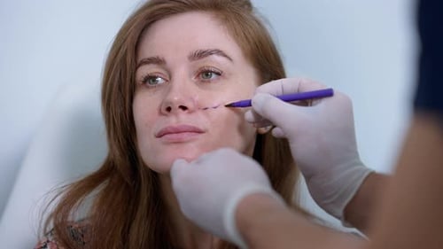 Closeup Face of Woman with Doctor Hand Drawing Markings for Facelift Procedure