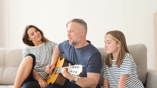Family Relaxing on Couch with Guitar Music