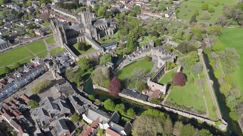 Orbital aerial view of medieval cathedral complex with soaring gothic spires, adjacent bishop’s pala