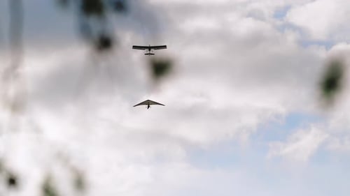 Ultralight Aircraft and Hang Glider Flying in Cloudy Sky