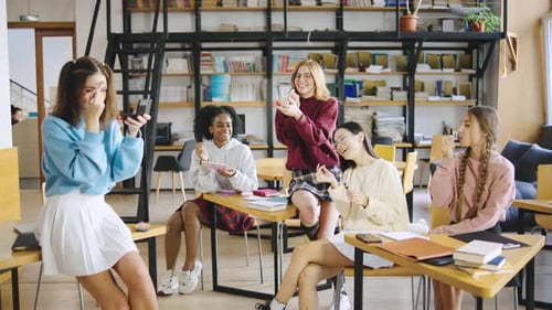 Estudantes multirraciais aproveitam o recreio na biblioteca da universidade e usam cosméticos, batom, blush e