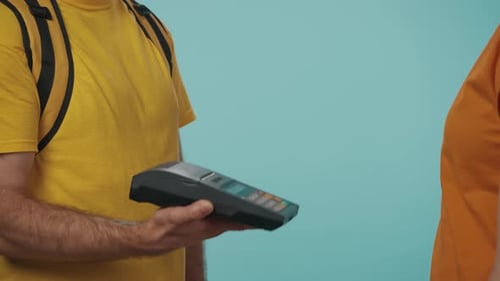 Closeup Shot of Delivery Man Giving a Female Customer Portable Terminal She Pays with Credit Card