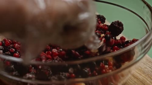 Gloved Hand Mixing Fresh Fruits in a Bowl