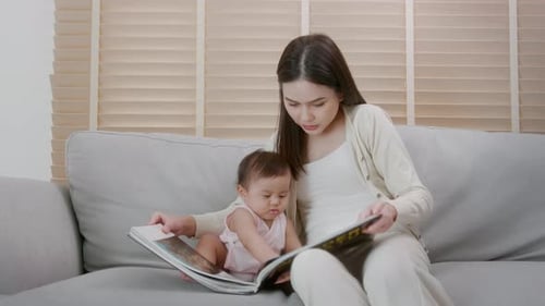 Woman Reading Picture Book with Infant on Sofa