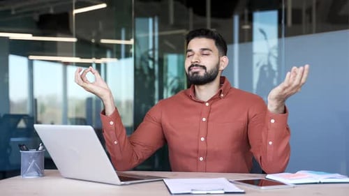 Young Man Meditating at Desk in Office