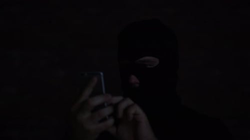 Person in Balaclava Using a Smart Phone