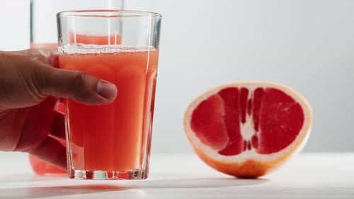 Glass of grapefruit juice placed beside fruit