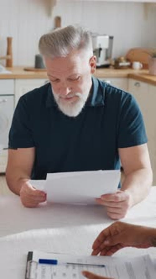 Vertical Portrait of Elderly Man Reading Agreement with Bank or Insurance Company Consultation with