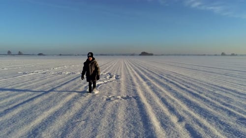Dolly shot of little boy walking on field full of snow