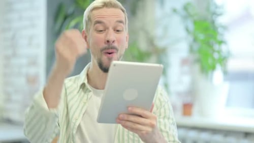 Excited Man Celebrates Success with Tablet
