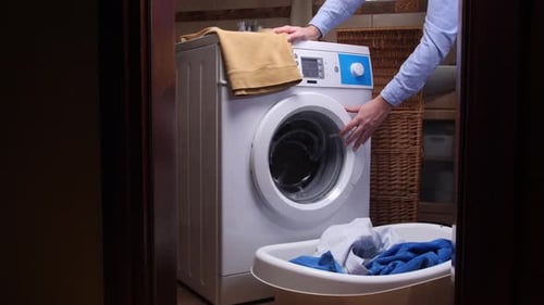 Person Opening Door of Washing Machine in Bathroom