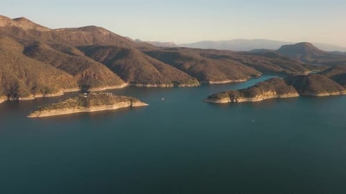 Aerial drone flying over a lake, water dam, with mountains at sunrise. Beautifull dreamy landscape v