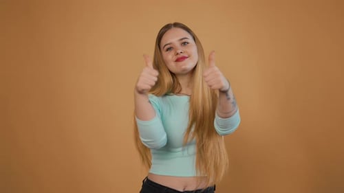 Junge, freudige Frau, die den Daumen nach oben hebt, Porträt eines Mädchens, das Handgesten zeigt, Genehmigung, Unterstützung, Zustimmen