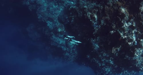 Woman Freediver Glides on the Deep in Tropical Ocean Near Reef Rocks