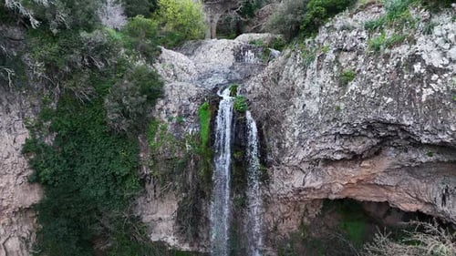 Aerial View of Serene Waterfall Cascading Into Lush Green Pool Surrounded by Vibrant Nature
