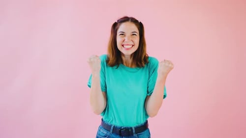 Cheerful Woman Celebrates Success in Front of Pink Backdrop
