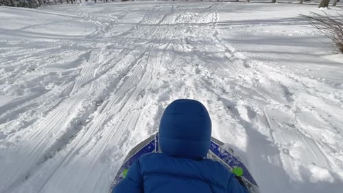 A child sleds headfirst down a snowy path